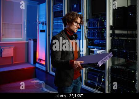 Portrait of it specialist holding hardware in hand standing in server room Stock Photo