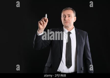 Mature business consultant with marker using virtual screen on dark background Stock Photo