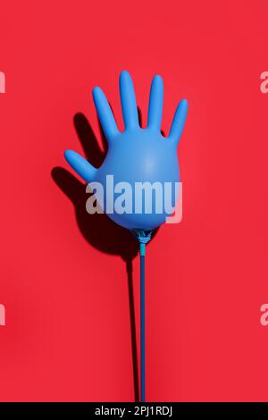 Inflated medical glove on red background Stock Photo