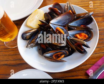 Steamed mussels with lemon wedge on white plate Stock Photo