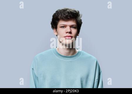 Headshot portrait of young male in casual sweatshirt, on gray background Stock Photo