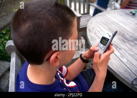 Teenage Boy in Garden Playing Game Snake on Nokia Mobile Phone Surrey England Stock Photo