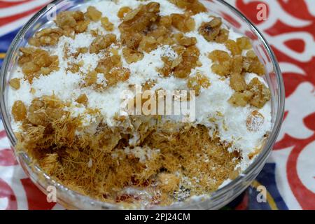 Konafa topped with whipped cream, raisins, walnuts, shredded coconut and stuffed with cream and fresh mango layer and soaked with honey sugar syrup, E Stock Photo