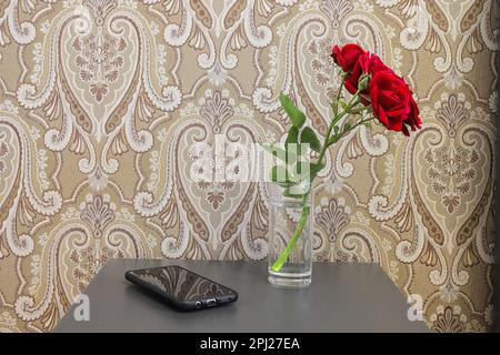 Red roses in the vase on the table in the bedroom Stock Photo