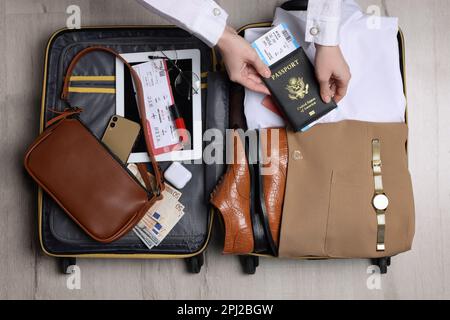 Woman packing suitcase for business trip on wooden floor, top view Stock Photo