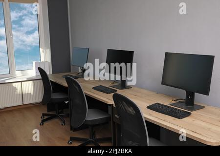Open office interior. Modern workplaces with computers near light grey wall Stock Photo
