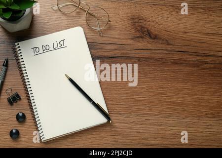 Flat lay composition with unfilled To Do list in notebook and glasses on wooden table, space for text Stock Photo