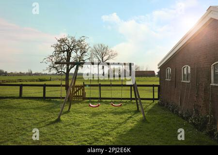 Outdoor swings near building on spring day Stock Photo