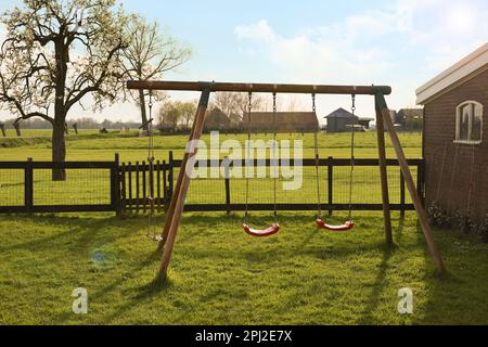 Outdoor swings near building on spring day Stock Photo