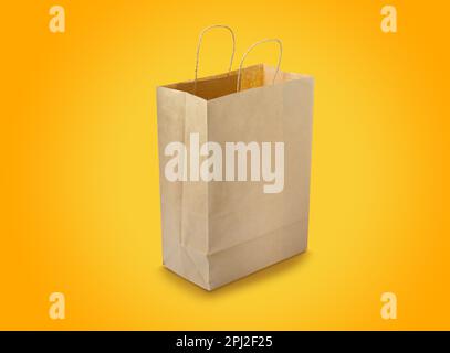 Kraft paper bag on yellow background. Mockup for design Stock Photo