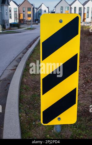 Safety sign yellow and black on an urban street. Yellow and black arrows. Street sign warning yellow black caution pattern. Nobody, selective focus Stock Photo