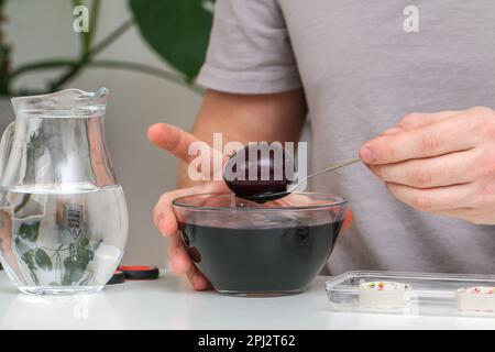 A man takes out colored Easter eggs from colored water. Dyeing easter eggs with food coloring is the first step in favorite Easter egg decorating idea Stock Photo