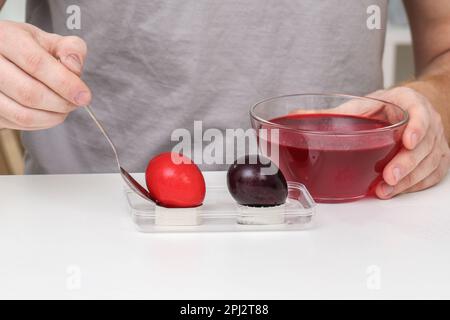 A man takes out colored Easter eggs from colored water. Dyeing easter eggs with food coloring is the first step in favorite Easter egg decorating idea Stock Photo