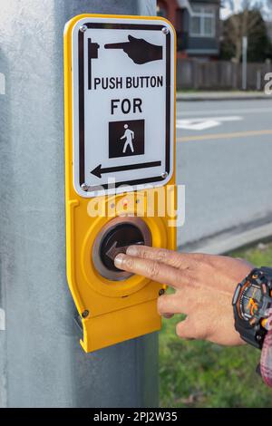 Hand pressing a button at traffic lights on pedestrian crossing. Pushing button for traffic light. Button of the mechanism lights traffic lights on th Stock Photo