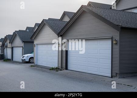 Row of garage doors at parking area for townhouses. Private garages for storage or cars in rows in an alley. Street photo, nobody Stock Photo