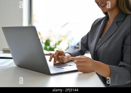 Close-up image of a confident and elegant millennial Asian businesswoman using her laptop to manage her business tasks. scrolling on website, browsing Stock Photo