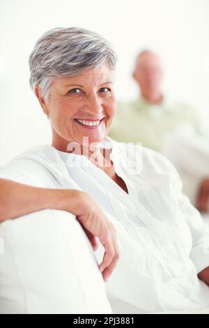 Relaxed mature woman smiling with man. Portrait of relaxed mature woman smiling with man in background. Stock Photo