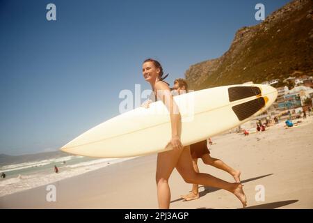 Catching some waves over the weekend. a couple surfing together at their favourite beach. Stock Photo
