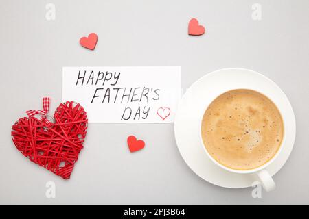 Fathers Day message with coffee cup and hearts on grey background. Top view Stock Photo