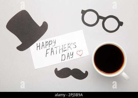 Father's day concept of coffee cup with mustache and hat on grey background Stock Photo