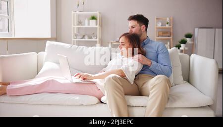 Family Couple Using Laptop And Tablet On Couch Stock Photo