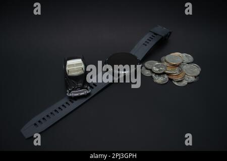 Concept for wealthiness and financial planning. A photo of a car, smartwatch, and pile of coins, after some edits. Stock Photo