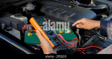Technician checking car battery voltage Stock Photo