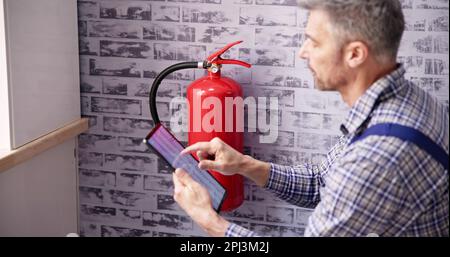 Worker Installing Fire Extinguisher. Inspection Service. Checking Security Label Stock Photo