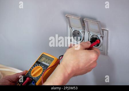 Male Electrician Checking Voltage Of Socket With Multimeter In House Stock Photo