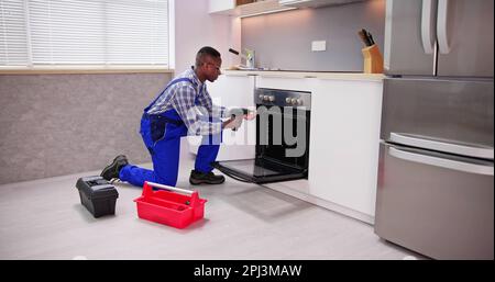 Male Worker Repairing Oven Appliance In Kitchen Room Stock Photo