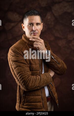 Man with serious expression posing in studio against brown background Stock Photo