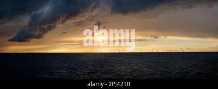 A storm arriving in the North Sea off the English coast at sunset with a windfarm on the horizon. dramatic sky, clouds and light on the ocean. Stock Photo