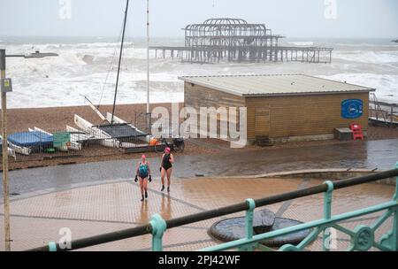 Brighton UK 31st March 2023 - Early morning swimmers brave the weather on Brighton seafront as storms batter the South Coast today with winds forecast to reach 70mph in some areas : Credit Simon Dack / Alamy Live News Stock Photo