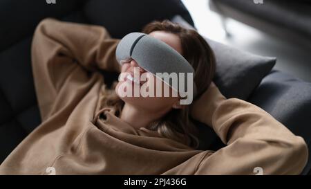 Woman with eye massage device lying on sofa Stock Photo