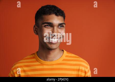 Young black man with piercing smiling and looking aside isolated over red background Stock Photo