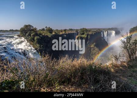 Exterior shot of a rainbow in front of Victoria Falls, Zimbabwe, on an afternoon. Stock Photo