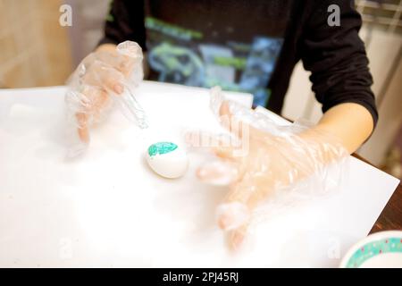coloring chicken eggs for the holiday of Easter, gloved hands, coloring eggs Stock Photo