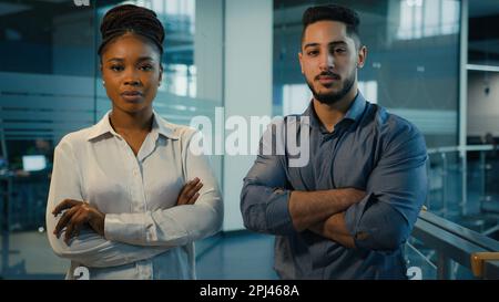 Business diverse coworkers two confident multiracial ethnic colleagues in office posing with crossed hands corporate portrait. African American Stock Photo