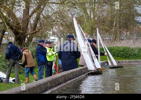 Older men on a cold spring day sail their lovely model yachts on a dedicated pond Stock Photo