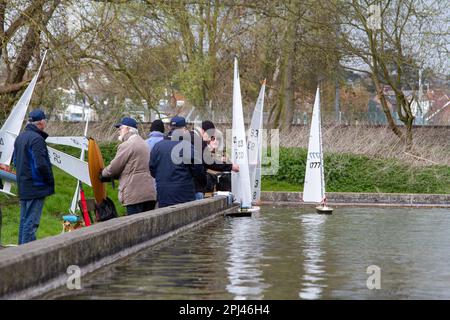 Older men on a cold spring day sail their lovely model yachts on a dedicated pond Stock Photo