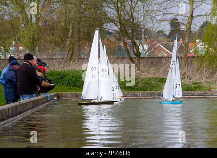 Older men on a cold spring day sail their lovely model yachts on a dedicated pond Stock Photo