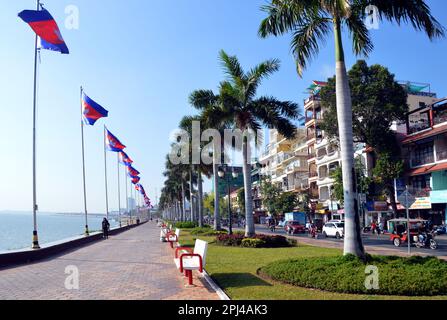Cambodia, Phnom Penh:  riverfront promenade with palm trees and flags, and Sisowath Quay (Road) behind. Stock Photo
