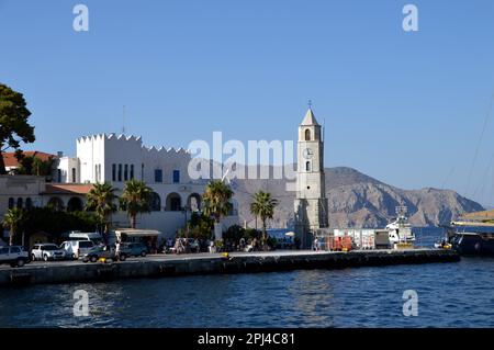 Greece, Island of Symi, Gialos:  the clocktower, built in 1881, with the police department (left) on the point, separating the two bays. Stock Photo