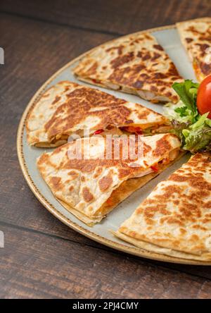 Mexican quesadilla with chicken, cheese and peppers on wooden table Stock Photo