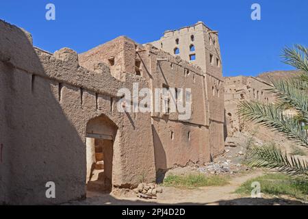 Oman, Birkat al Mawz:  entrance to the village of abandoned mudbrick buildings at the foot of a spectacular stone outcrop, surrounded by a sea of date Stock Photo