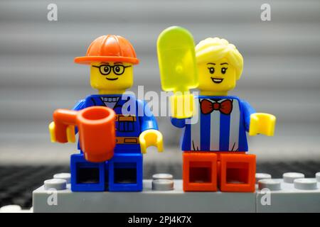 A Lego construction worker and saleswoman having a break while eating ice cream and drinking. Stock Photo