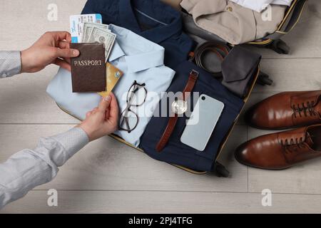 Man packing suitcase for business trip on wooden floor, top view Stock Photo