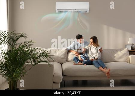 Happy family resting under air conditioner on beige wall at home Stock Photo