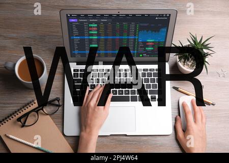 Influence of war on stock exchange. Woman analyzing electronic trading platform on laptop at wooden table, top view Stock Photo