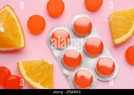 Many orange cough drops on pink background, flat lay Stock Photo